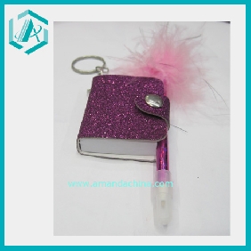 A Small Unique Design Notebook With A Feather Pen And A Button